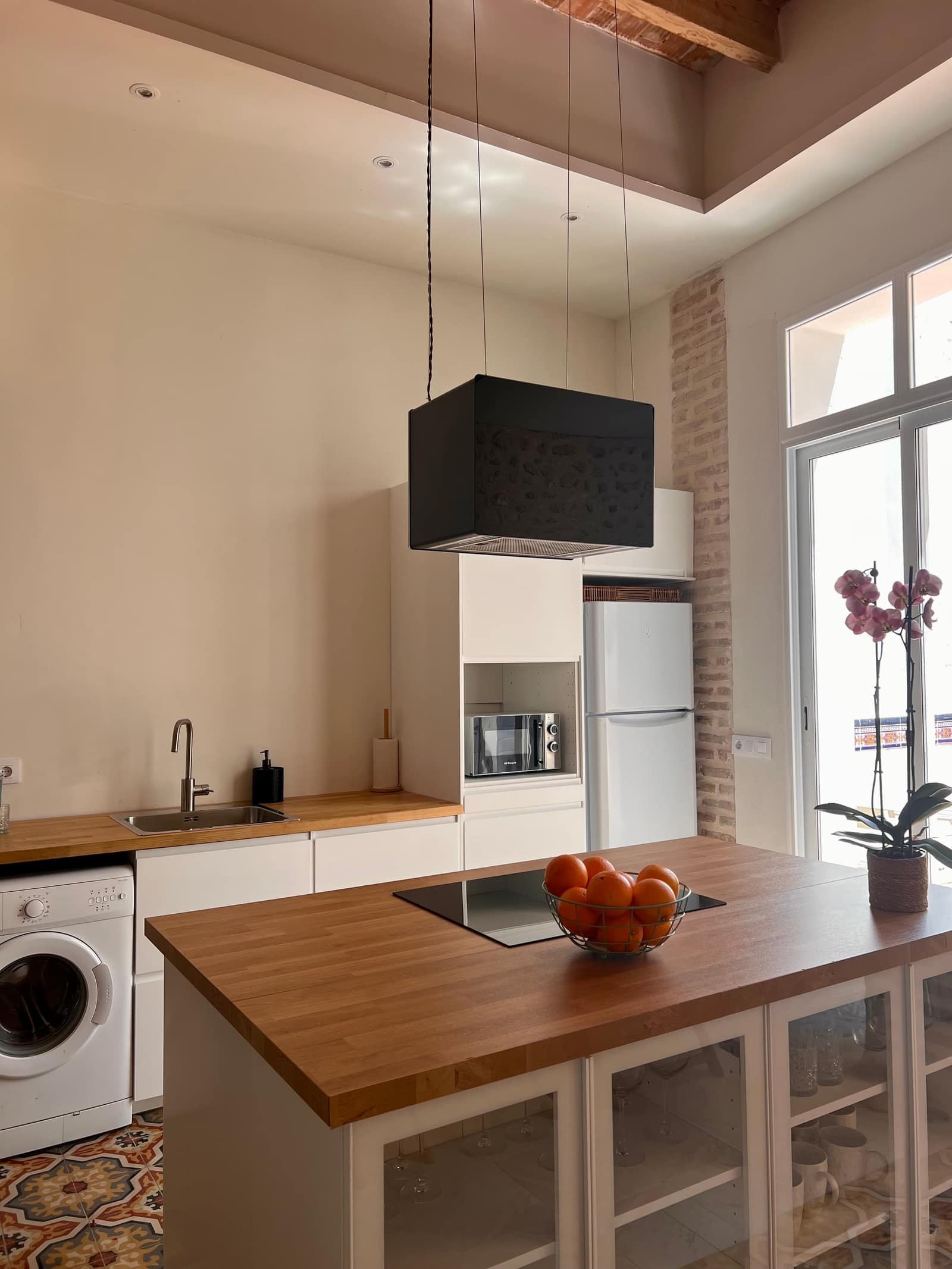 Cocina moderna con isla de madera, campana negra y suelo hidraulico - Casa Filo Xeresa